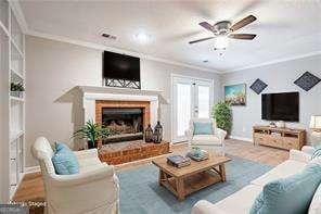 living area featuring ornamental molding, a brick fireplace, ceiling fan, wood finished floors, and baseboards