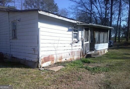 view of home's exterior with a sunroom and a yard