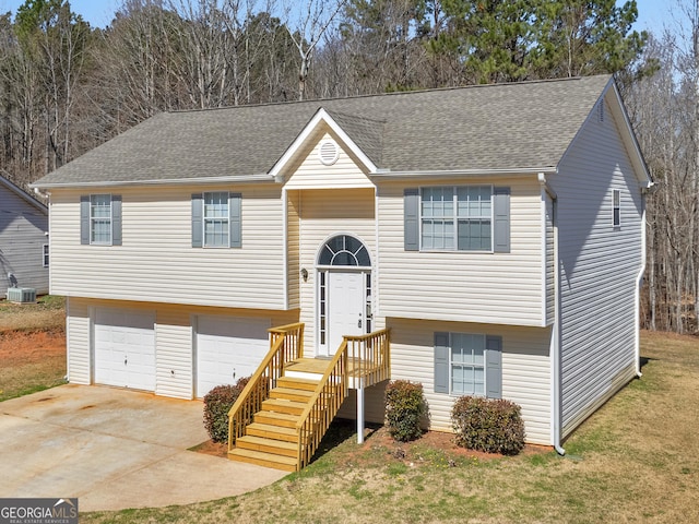 split foyer home with an attached garage, a front lawn, concrete driveway, and roof with shingles