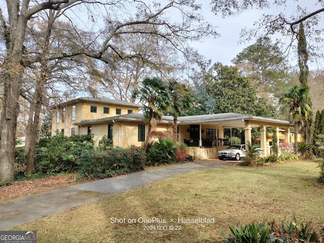 view of front facade featuring an attached carport, aphalt driveway, stucco siding, and a front lawn