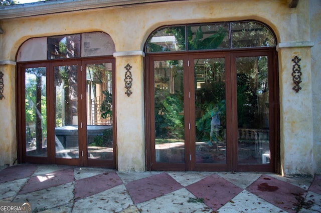 entrance to property featuring french doors, a patio, and stucco siding