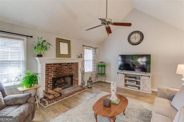 living area with a brick fireplace, wood finished floors, and a healthy amount of sunlight