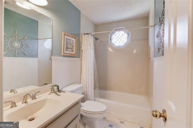 bathroom with shower / bath combo, wainscoting, vanity, and toilet