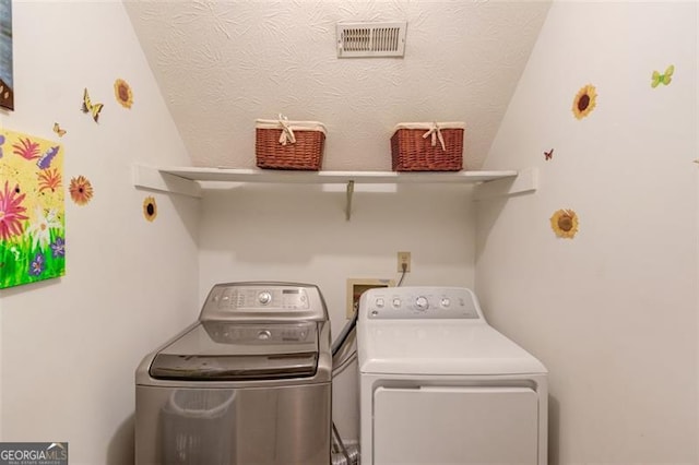 washroom featuring laundry area, visible vents, a textured ceiling, and separate washer and dryer