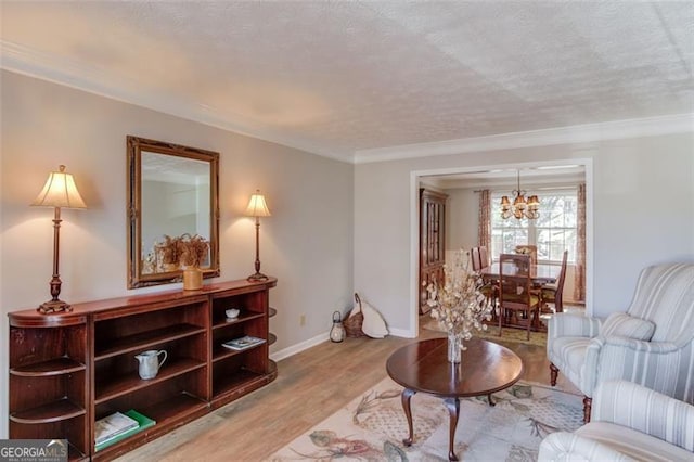 living room featuring crown molding, an inviting chandelier, a textured ceiling, light wood-type flooring, and baseboards