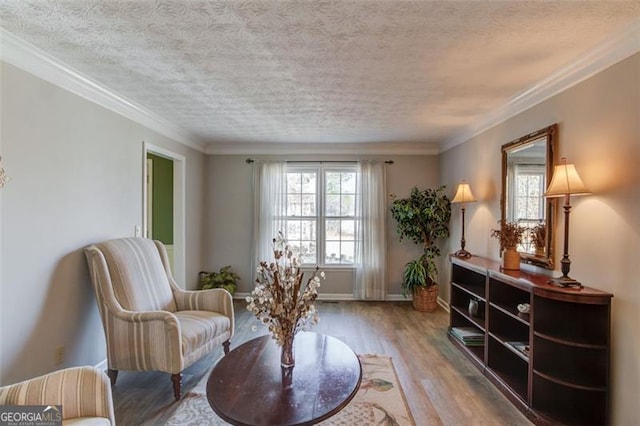 living area featuring baseboards, a textured ceiling, ornamental molding, and wood finished floors