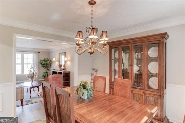 dining space with crown molding, an inviting chandelier, and wood finished floors