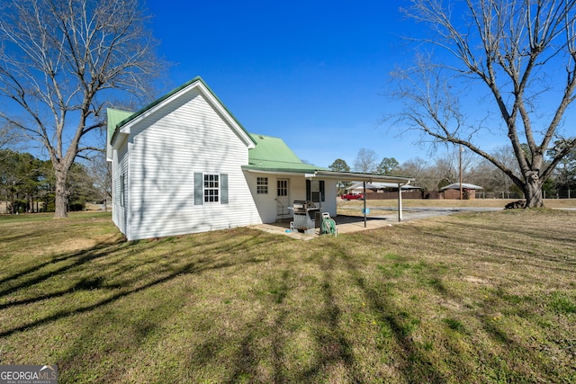 back of house featuring a carport, metal roof, a yard, and a patio