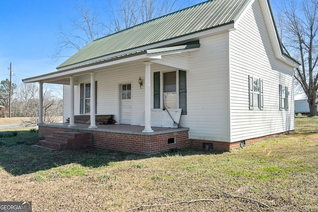 view of front facade with crawl space, metal roof, a front lawn, and a porch