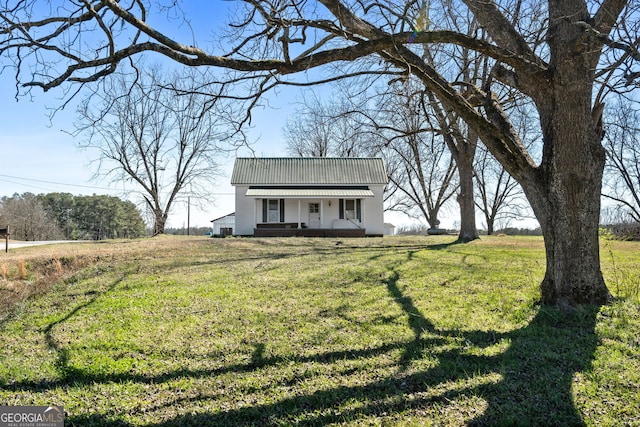 view of front facade with covered porch, metal roof, and a front yard