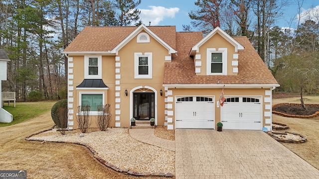 traditional home with a garage, a shingled roof, decorative driveway, and stucco siding