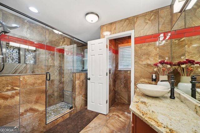 full bath with a stall shower, tile walls, and vanity