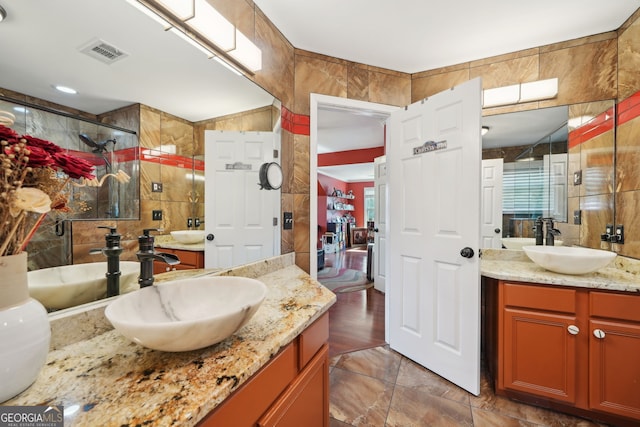 bathroom featuring tile walls, visible vents, a sink, and tiled shower