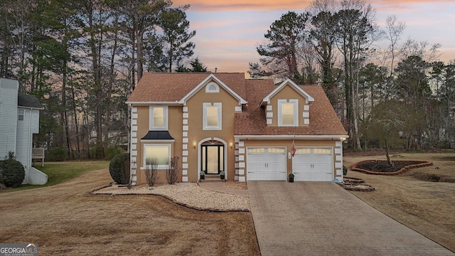 traditional home with a garage, roof with shingles, a yard, and decorative driveway