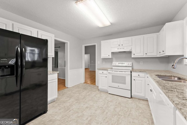 kitchen with under cabinet range hood, white appliances, a sink, white cabinetry, and light stone countertops