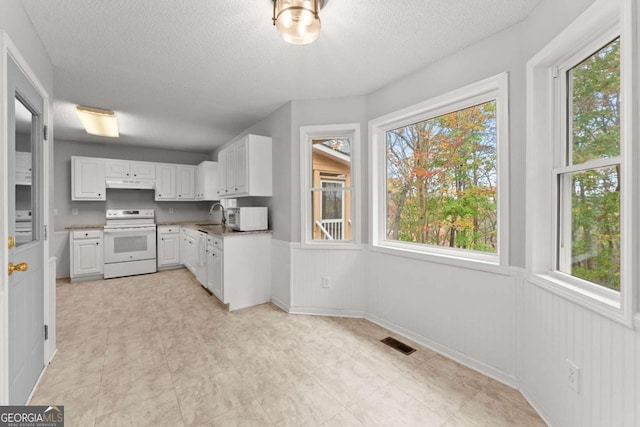 kitchen with white electric stove, visible vents, under cabinet range hood, white cabinetry, and a sink