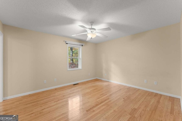 empty room featuring baseboards, visible vents, a ceiling fan, a textured ceiling, and light wood-type flooring