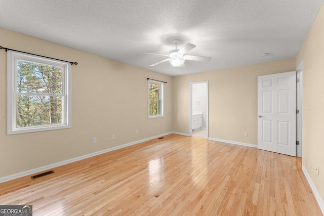 unfurnished bedroom featuring light wood-style floors, visible vents, a textured ceiling, and baseboards