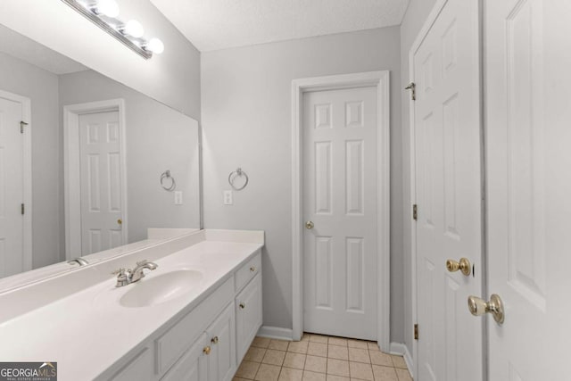 bathroom featuring tile patterned flooring, baseboards, a textured ceiling, and vanity