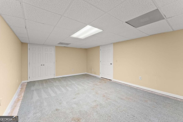 below grade area featuring a paneled ceiling, carpet flooring, and baseboards