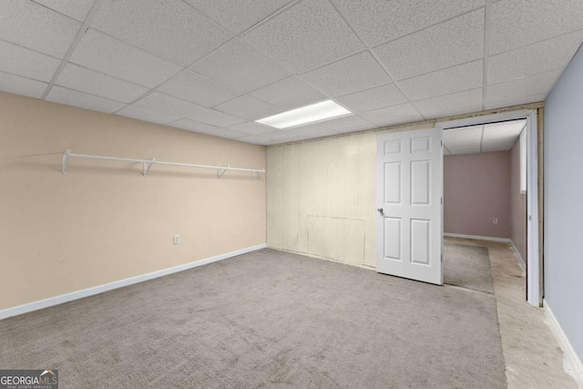 below grade area featuring carpet floors, a drop ceiling, and baseboards