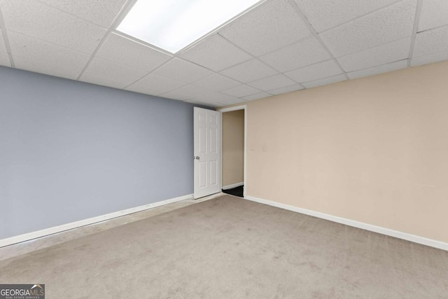 empty room featuring carpet, a drop ceiling, and baseboards