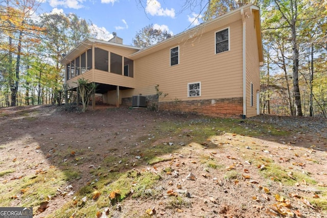 back of property featuring a sunroom, a chimney, and central AC unit