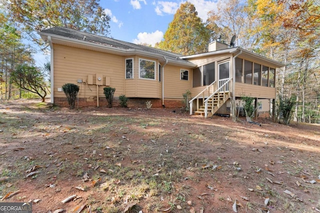 rear view of house featuring a chimney and a sunroom