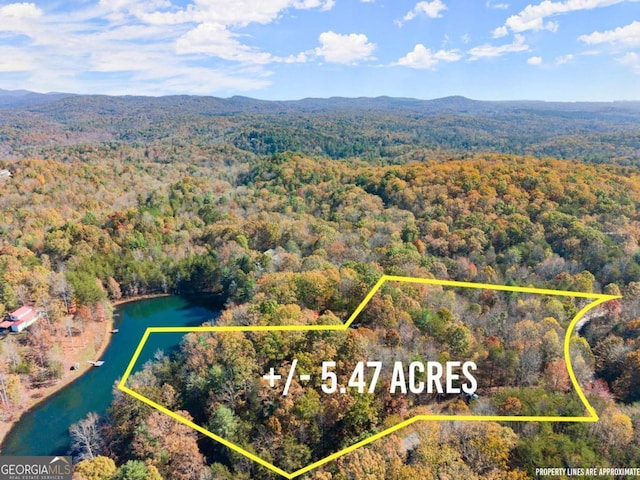 aerial view with a water and mountain view and a wooded view