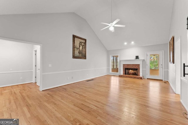 unfurnished living room featuring visible vents, light wood-style floors, a brick fireplace, ceiling fan, and high vaulted ceiling