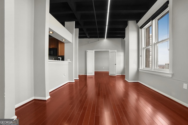 unfurnished living room with baseboards and wood finished floors