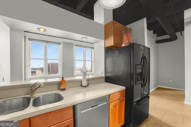 kitchen featuring light tile patterned floors, a sink, light countertops, black fridge, and dishwasher