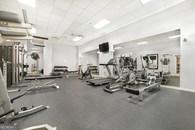 gym with visible vents, a paneled ceiling, and baseboards