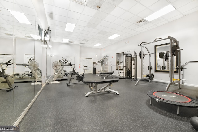 exercise room with baseboards, visible vents, and a drop ceiling