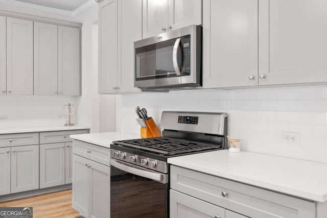 kitchen with backsplash, appliances with stainless steel finishes, gray cabinets, and light countertops