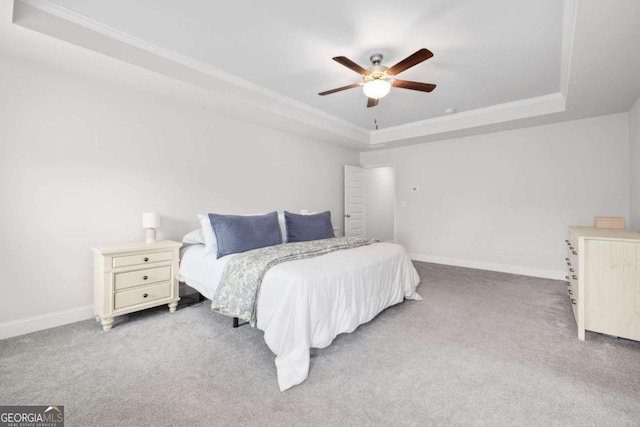 bedroom with carpet, baseboards, a raised ceiling, and crown molding