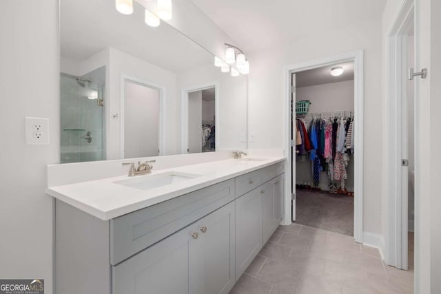 full bathroom with a tile shower, a sink, a spacious closet, and double vanity