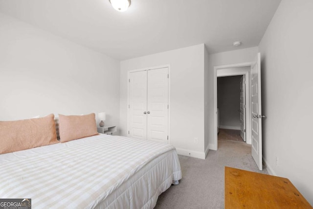 bedroom with a closet, light carpet, and baseboards