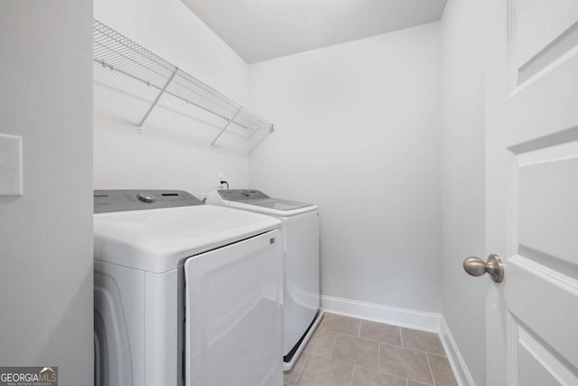 clothes washing area with laundry area, light tile patterned floors, baseboards, and washer and dryer