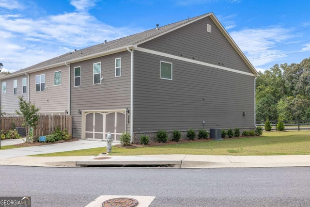 view of side of home featuring a garage, concrete driveway, central AC, and fence