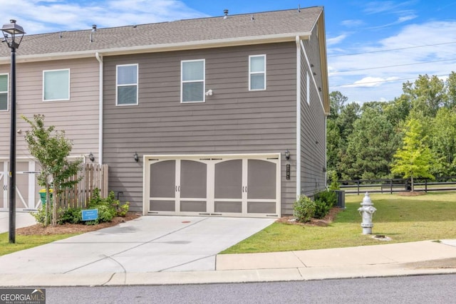 view of side of property with concrete driveway, a lawn, and fence