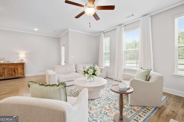 living room featuring baseboards, visible vents, a ceiling fan, ornamental molding, and wood finished floors