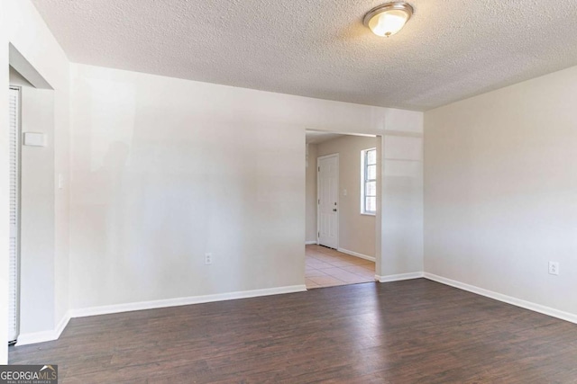 unfurnished room with a textured ceiling, baseboards, and wood finished floors