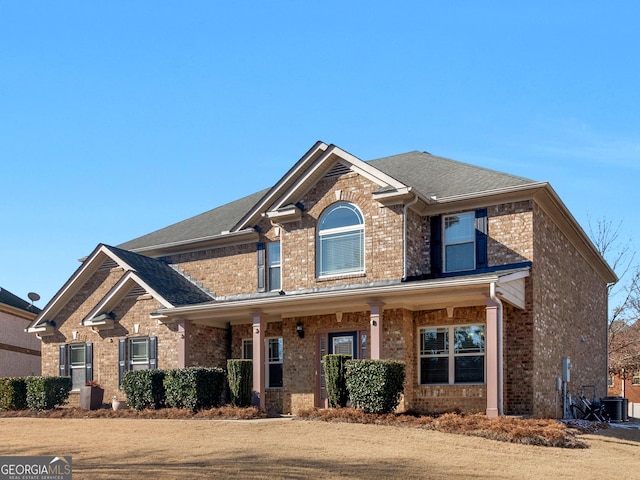 view of front of home featuring brick siding and roof with shingles