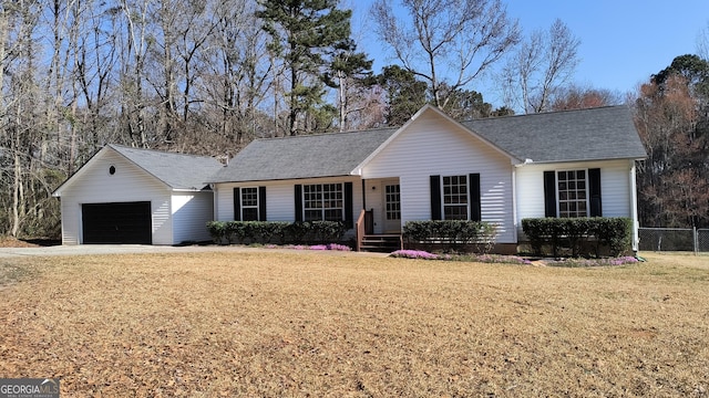 ranch-style home with roof with shingles, an attached garage, fence, and a front yard