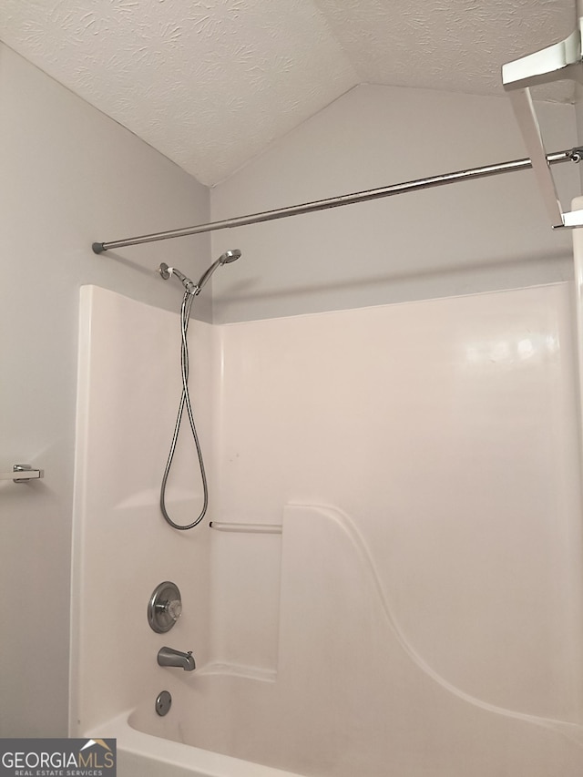 full bathroom featuring lofted ceiling,  shower combination, and a textured ceiling