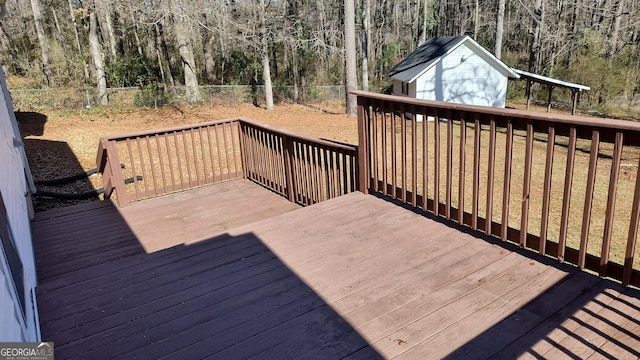 wooden deck with an outdoor structure, fence, and a wooded view