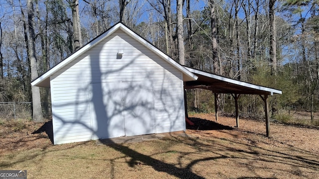 view of shed featuring a wooded view, fence, and a carport