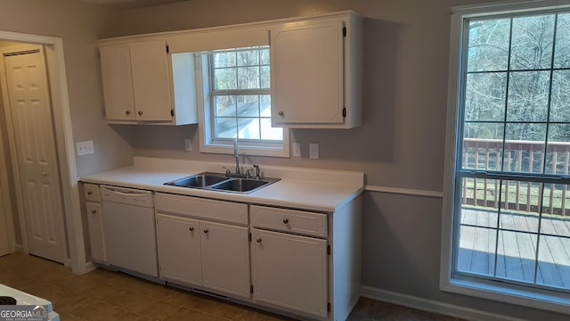 kitchen with white dishwasher, white cabinetry, and a sink