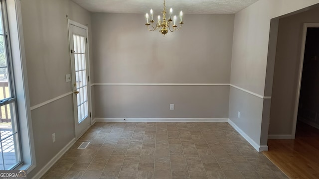 unfurnished dining area with visible vents, baseboards, and a notable chandelier